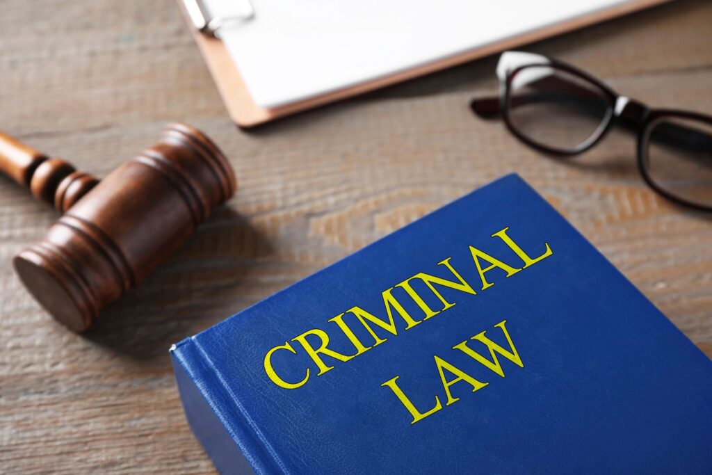 Criminal law book with gavel and glasses.